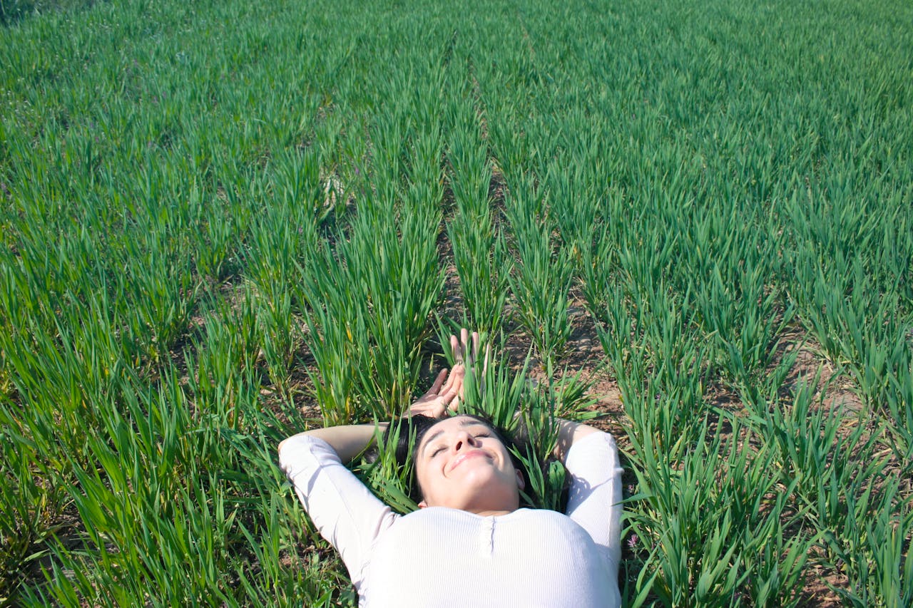 Woman relaxing in a lush green field enjoying a sunny day in Brescia, Italy.